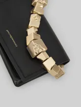 Bolso de mano negro de poliéster con asa rígida dorada con forma de cubos.