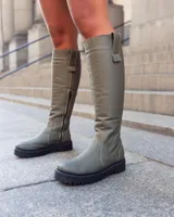Bota de caña alta en color verde militar, con diseño moderno y suela gruesa.