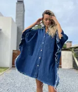 Camisola tipo poncho en jean azul oscuro con cuello camisero, cierre frontal con botones, mangas cortas amplias con volados y ruedo con flecos.