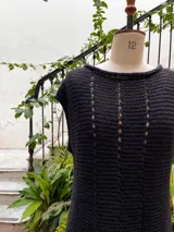 Chaleco color crudo tejido a mano en hilado 100% baby alpaca, con cuello tipo bote, hombros anchos, puntos calados en frente y espalda, y tajos laterales en el bajo.