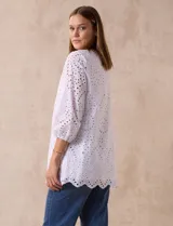 Blusa blanca de algodón con bordado broderie, cuello a la base con escote en V y mangas tres cuartos amplias con puño elastizado.