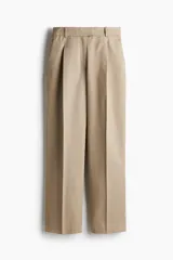 Pantalón color beige de corte holgado en sarga de algodón. Modelo de tiro alto con cierre, pretina prolongada con botón oculto y corchetes, bolsillos al bies y bolsillos insertados atrás. Piernas rectas con pinzas y pliegues adelante y atrás.