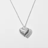 Colgante en forma de corazón, elaborado en bronce plateado con diseño estriado.