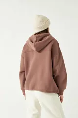 Campera marrón de felpa con cierre, capucha ajustable y bolsillos frontales tipo canguro.