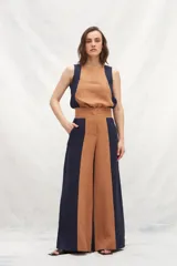 Pantalón de lino de tiro alto, con corte amplio a la cintura, confeccionado en dos colores: azul marino y marrón. Presenta un recorte delantero que estiliza la silueta. De calce cómodo.