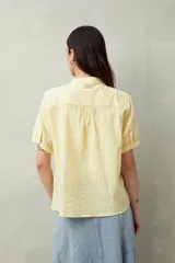 Camisa blanca de manga corta abullonada, cuello mao y botones forrados.