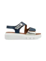 Sandalia con plataforma blanca, base marrón y tiras de cuero metalizado azul marino y plateado, con ajuste de velcro en el tobillo y el empeine.
