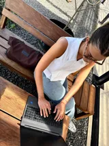 Bolso tote marrón de gabardina con detalles de cuero negro, asas cortas y cierre superior.