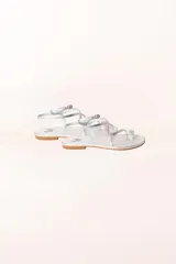 Sandalia plana plateada con tiras finas y cierre con hebilla en el tobillo.