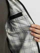 Campera aviadora negra de corte clásico, con cuello camisero, cierre frontal con cremallera, bolsillos laterales y puños ajustados. Confeccionada en tejido plano de poliéster y algodón.