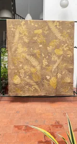 Mantel rectangular grande de algodón con estampado botánico en tonos dorados sobre fondo marrón.