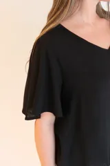 Blusa negra de tela liviana con escote en V y mangas cortas con volados.