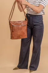 Cartera tipo bandolera de tamaño mediano confeccionada en símil cuero color marrón. Presenta una correa larga regulable, dos compartimientos principales y un bolsillo frontal con cierre de cremallera.