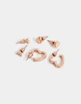 Set de tres pares de aros bañados en oro rosa: un par de aros tipo argolla, un par de aros tipo botón con forma de corazón y un par de aros tipo botón con forma triangular y strass.
