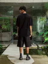 Camisa de manga corta color crudo/blanco, confeccionada en tejido de punto abierto con textura calada y cuello polo. Presenta cierre frontal de botones.