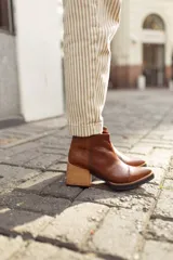 Bota corta de cuero color marrón con textura reptil, caña baja, cierre lateral y taco ancho.