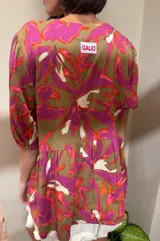 Blusa de calce holgado con estampado floral en tonos marrones, fucsias, naranjas y blancos. Escote en V con doble lazo ajustable y mangas 3/4 con volumen.