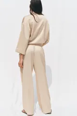 Pantalón de tiro alto color beige con cintura elástica ajustable con cordones, bolsillos delanteros y pernera ancha.