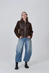 Campera estilo aviador con cuerpo de eco-cuero marrón oscuro y mangas y cuello de corderito (teddy) marrón. Presenta cierre frontal metálico y dos bolsillos frontales con solapa de corderito.