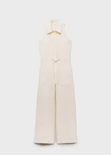 Mono largo color crudo, sin mangas, con cuello camisero, cierre frontal con botones, cintura ajustable con lazo y bolsillos delanteros y traseros. Diseño recto.