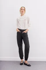 Pantalón babucha negro de lyocell satinado, con elástico en la botamanga, bolsillos plaqué con remaches metálicos y bolsillos cargo en las piernas.