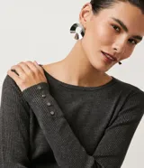 Suéter de punto color verde, con cuello barco, mangas largas y textura acanalada.