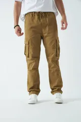 Pantalón cargo color beige, con cintura elástica ajustable con cordón, bolsillos laterales con cierre y bolsillos cargo con solapa.