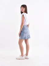 Minifalda blanca de denim con corte evasé y ruedo desflecado.
