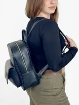 Mochila grande de cuero negro con bolsillo frontal de charol y cierre superior.