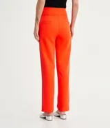 Conjunto sastrero color naranja, compuesto por un blazer entallado con solapas de muesca, cierre con lazo y pantalón de vestir recto de tiro alto.