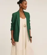 Vestido midi color crema, de corte suelto con escote redondo y breteles finos. Presenta un recorte con frunce en la parte inferior.