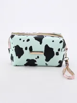 Necesser rectangular con estampado de manchas de vaca en tonos celeste y negro, con cierre superior dorado y tira de agarre lateral.