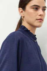 Camisa azul de manga larga con cuello con volados y puños con volados.