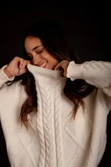 Sweater tejido de punto color rosa pastel, con cuello alto y diseño de trenzas verticales.