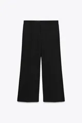 Pantalón negro de tiro medio con trabillas en la cintura, pernera recta y corte cropped. Cierre frontal con cremallera y ganchos metálicos.