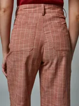 Pantalón de lino color ladrillo con estampado a cuadros blancos, de corte palazzo y tiro alto.