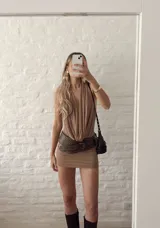 Vestido corto color beige, con escote halter y espalda descubierta. Ajustado al cuerpo y confeccionado en microtul.