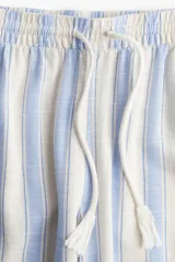 Pantalón de tejido liviano de mezcla de lino y viscosa a rayas celestes y blancas. Modelo de corte holgado con elástico revestido y cordón para ajustar en la cintura. Piernas rectas con bolsillos al bies.