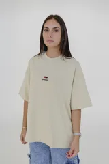 Remera color beige de corte holgado, con cuello redondo y mangas cortas. Estampado pequeño en el pecho con el logo de la marca Pulau.