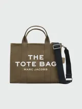 Bolso tote mediano color verde militar, con doble asa corta y correa larga extraíble de tela negra. Estampado frontal con el texto "THE TOTE BAG MARC JACOBS" en letras blancas.