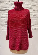 Sweater tejido a mano en lana merino color crema, con cuello alto tipo polerón y mangas largas.