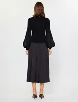 Conjunto de dos piezas compuesto por un sweater negro de punto acanalado con mangas globo de organza transparente y una falda midi negra de satén con caída suelta y cintura elastizada.