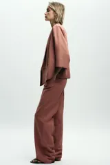 Pantalón de vestir color beige, de tiro alto, con cintura elástica en la parte trasera, bolsillos delanteros y falsos bolsillos de vivo en la parte trasera.