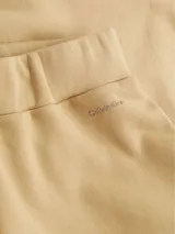 Pantalón de jogging color beige, de corte relajado, con cintura y tobillos elásticos, bolsillos laterales y logo pequeño en el lateral.