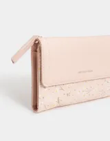 Billetera color rosa pálido con estampado de flores pequeñas, formato fichero con solapa y tag en relieve. Tiene cierre superior con puller, solapa con broche, compartimento para tarjetas y bolsillo interno con solapa.