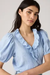 Blusa celeste con estampado floral, cuello en V con volantes, mangas cortas abullonadas y cierre frontal con botones.