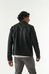 Campera de cuero sintético negra con cuello mao, cierre frontal con cremallera, bolsillos laterales con cremallera y detalle de costuras en los hombros.