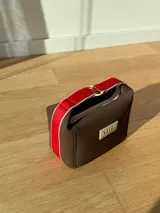 Neceser color beige de forma rectangular, con cierre superior y asa de mano.