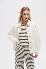 Campera de jean color crudo, de corte recto, con cuello clásico, cierre frontal con botones metálicos, dos bolsillos con solapa en el pecho y bajo con detalle de bordado calado.