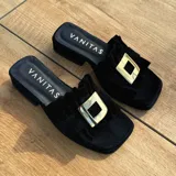 Zuecos negros de cuero vacuno, con capellada fruncida y horma cuadrada.